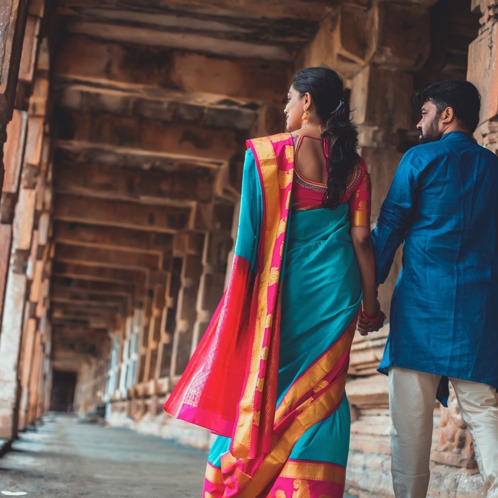 candid pre wedding picture of bride and groom holding hands and walking in a temple