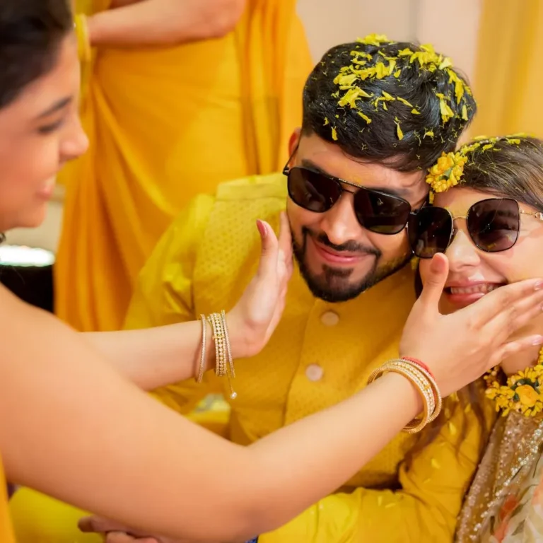 Candid wedding photography of a family friend applying haldi to Pranjal and Vineeta.