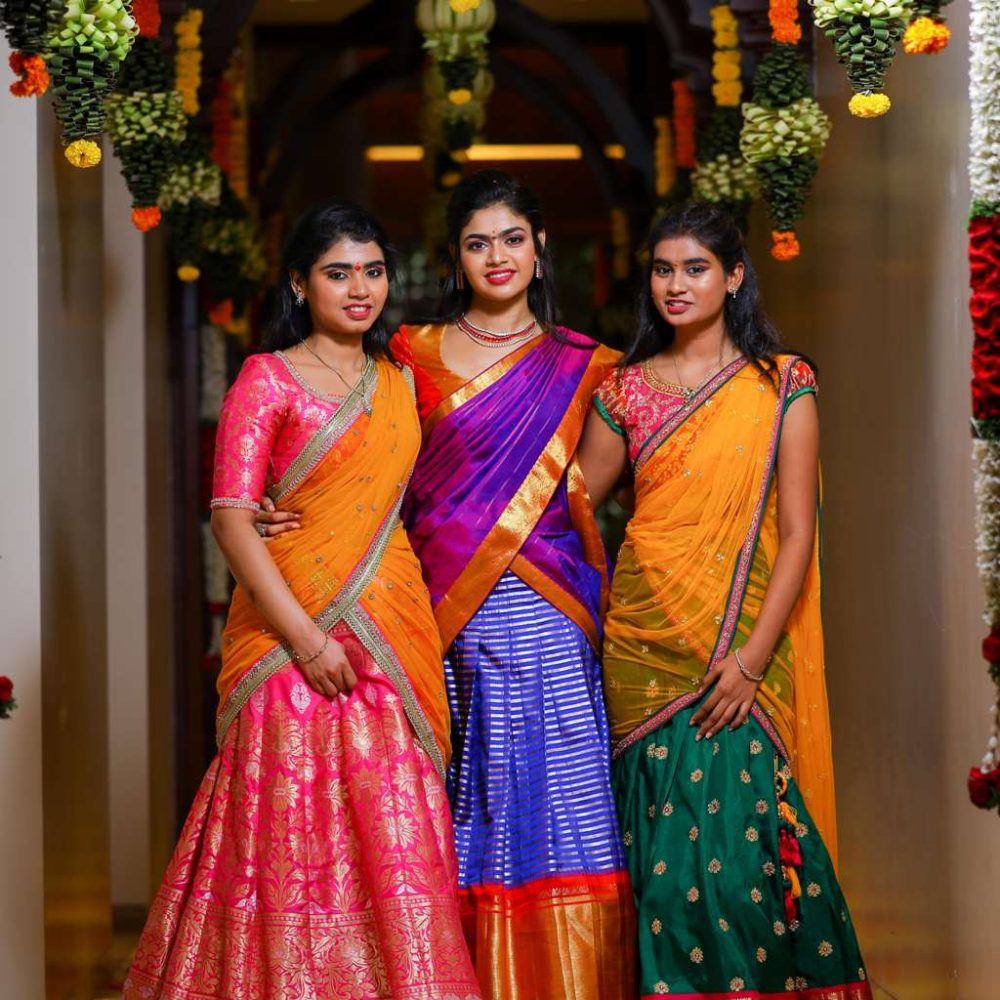 picture of bride with her sisters wearing saree in a decorated hallway